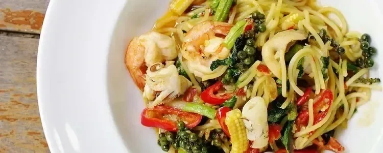 A photo of a bowl of shrimp and mixed vegetable pasta