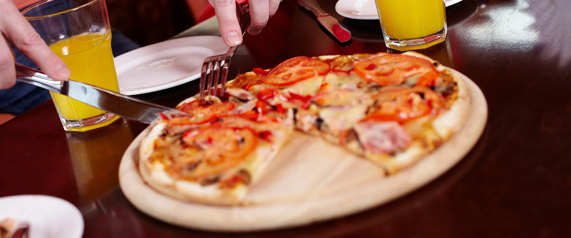 A photo of someone cutting into a delicious tomato and cheese pizza